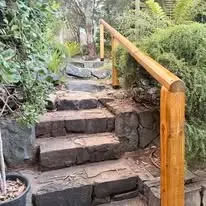 Timber handrail on stone garden steps.